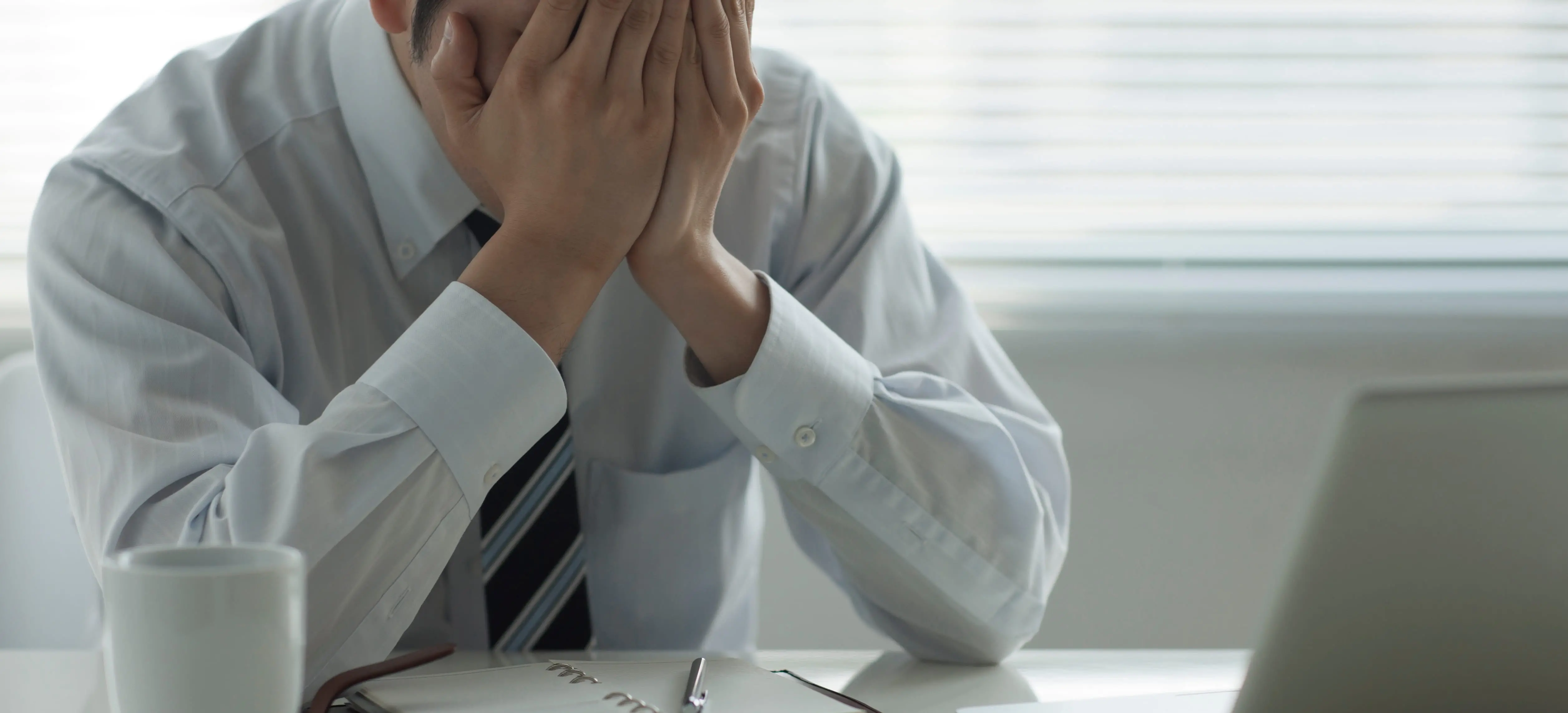 男性が顔を両手で覆っている様子